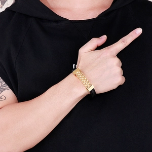 Close-up of men's black braided leather bracelet with golden wave pattern metal buckle