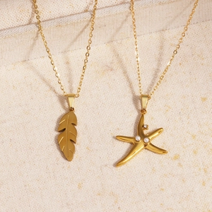 Detail view of gold leaf and starfish pendants with pearl accents on linen background