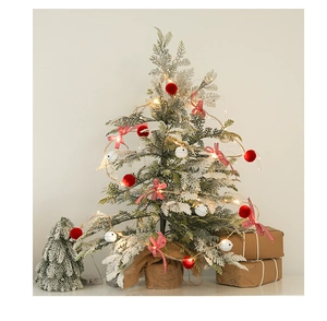 Close-up of a mini Christmas tree with red berries, pine cones, and warm LED fairy lights