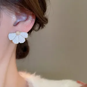 Boucles d'oreilles fleurs en émail blanc avec centre doré sur un mannequin femme