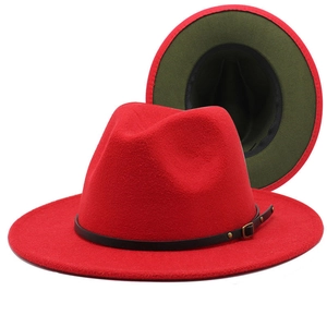 Detail of red fedora hat with green underbrim and black decorative leather belt strap