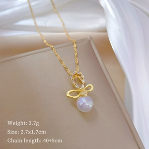 Detail of gold bow necklace pendant with sparkling crystals and a glowing faux pearl