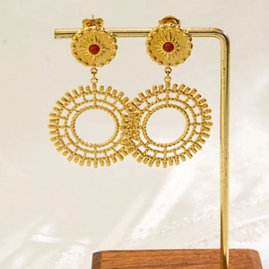 Detail of bohemian gold titanium earrings with red stone and sunburst radiant texture
