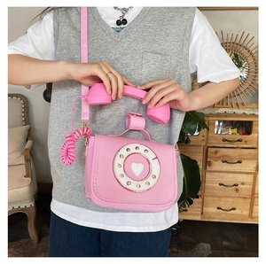 Detail view of a creative pink telephone shaped crossbody bag on a model.