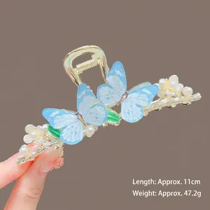 Detail of blue fishtail butterfly hair claw clip with pearls and gold metal frame