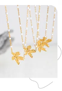 Dettaglio di ciondoli a fiore placcati in oro PVD su collane con delicate perline bianche