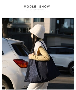 Outdoor lifestyle view of a large navy blue nylon tote bag worn on a woman's shoulder