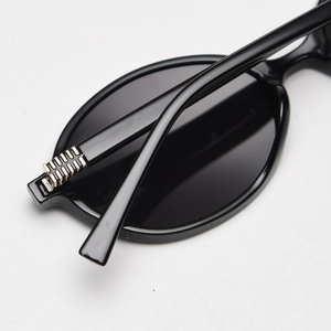 Detailed view of hinge with multi-row silver metal gear accents on black oval sunglasses