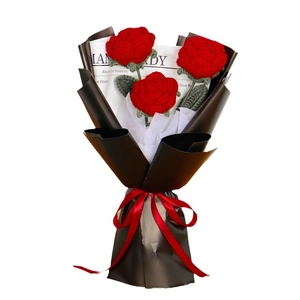 Handmade knitted bouquet with three red roses in vintage newspaper style wrapping