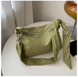 Detail of green canvas crossbody bag with knotted strap and silver metal chain link