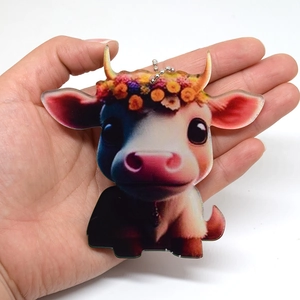 Close-up of a cute acrylic cow charm with a flower crown and bead chain hanging accessory