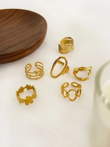 Detailed view of six 18K gold plated titanium steel rings with flower and chain designs
