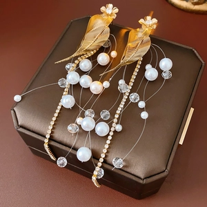 Detail shot of pearl tassel earrings with gold leaf design on premium leather background