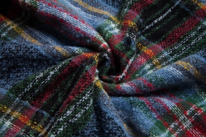 Close-up of thick Scottish plaid fabric with colorful wool texture and soft draped folds