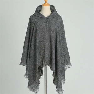 Detailed close-up of grey knitted hooded poncho with fringe hem for autumn winter seasons
