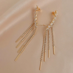 Elegant gold leaf tassel earrings with white zircon accents on champagne silk background