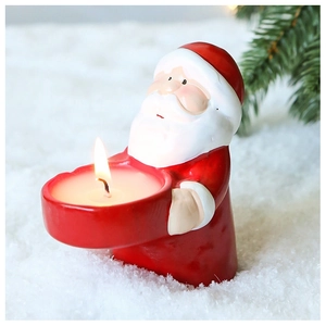Detailed view of a Santa Claus candle holder with a lit candle on artificial snow background