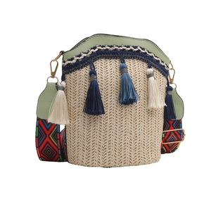 Detail of straw woven bucket bag with green PU leather trim and colorful geometric strap