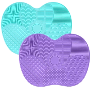 Silicone apple-shaped makeup brush cleaning mats in mint green and purple with suction cups