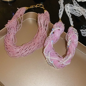 Detail of multilayer pink beaded necklaces with lace ribbons and pearl accents on a tray