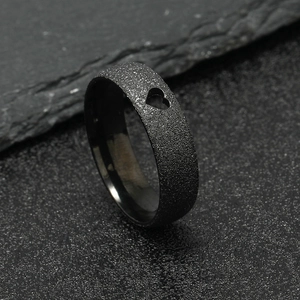 Matte black stainless steel ring with heart cutout on gray stone background