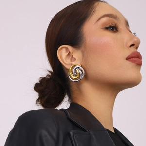 Close-up of twisted two-tone gold and silver earrings on a model with a minimalist style