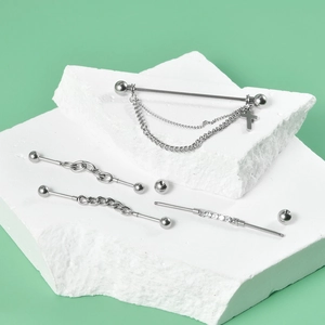 Detailed shot of silver industrial barbell earrings with cross pendant and zircon stones
