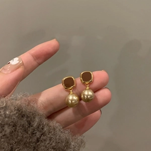 Detail view of French vintage earrings with dark square enamel and hanging pearl