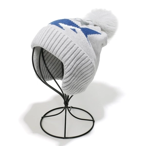 Detailed view of gray knit beanie with white pompom and star pattern for kids