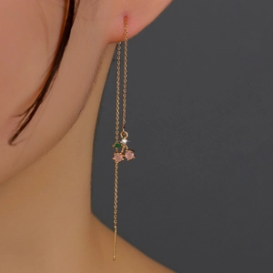 Close-up of gold chain earrings with pink and green cherry-shaped crystals on model