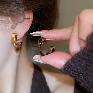 Close-up of leopard print resin C-shaped hoop earrings with a polished tortoiseshell finish