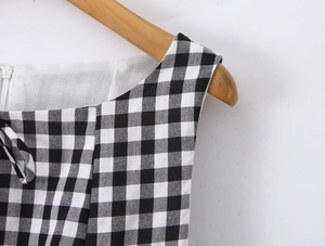Detail of black and white gingham dress neckline with clear fabric texture on wooden hanger
