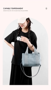Detail of light blue canvas tote bag showing top handles and adjustable shoulder strap