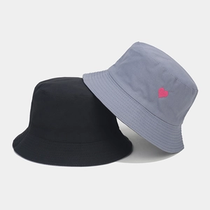 Détail de la petite broderie cœur rose sur les bobs en toile de coton noir et bleu