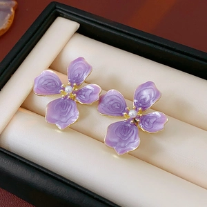 Vue macro de boucles d'oreilles fleurs violettes avec bords dorés et perles
