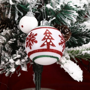 Close-up of white Christmas ornaments with red glitter snowflakes on tree branches