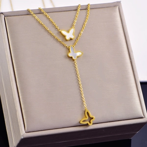 Close-up of golden double-layered butterfly necklace with white shell inlay details