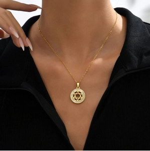 Close-up of a gold starburst necklace with mother of pearl inlay worn by a model