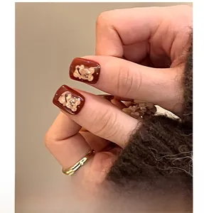 Macro detail of wine red press on nails with 3D golden bear and bow accents