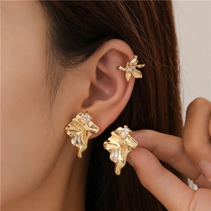 Detail of gold irregular lava texture ear cuff and stud earrings set with zircon