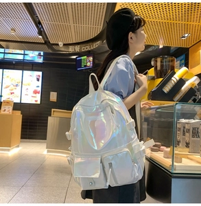 Detailed view of white holographic backpack with multi-pocket design in a cafe setting