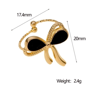 Detail view of gold bow ring with black enamel and dimensions of 20mm width and 2.4g weight