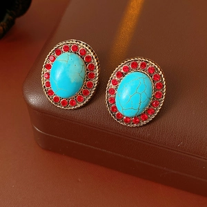 Detailed close-up of vintage oval gold earrings with turquoise stone and red rhinestones