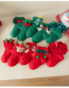 Flat lay of colorful Christmas baby socks with festive 3D bows and reindeer decorations
