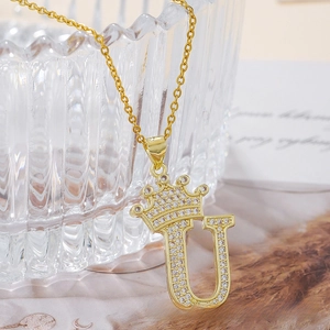 Macro detail of gold-plated crown and initial U pendant necklace with inlaid zircons