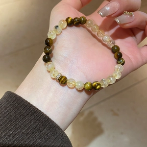 Detail of natural rutilated quartz and tiger eye beaded bracelet on a female wrist