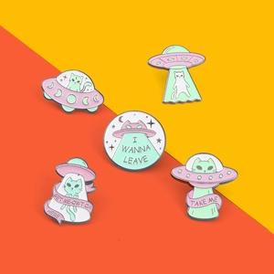 Détail de cinq broches émaillées chat et OVNI en rose et vert menthe sur fond coloré