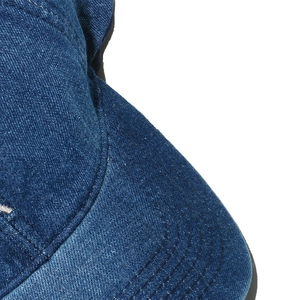 Detailed close-up of blue denim baseball cap fabric with visible twill texture and stitching