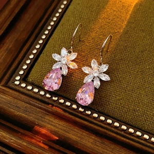 Vue macro des boucles d'oreilles fleur avec zircons roses sur présentoir en velours