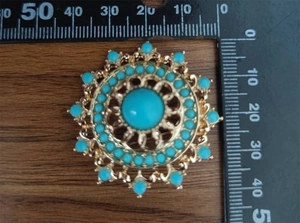 Detail view of ethnic hollow geometric brooch with turquoise stones and 45mm ruler scale